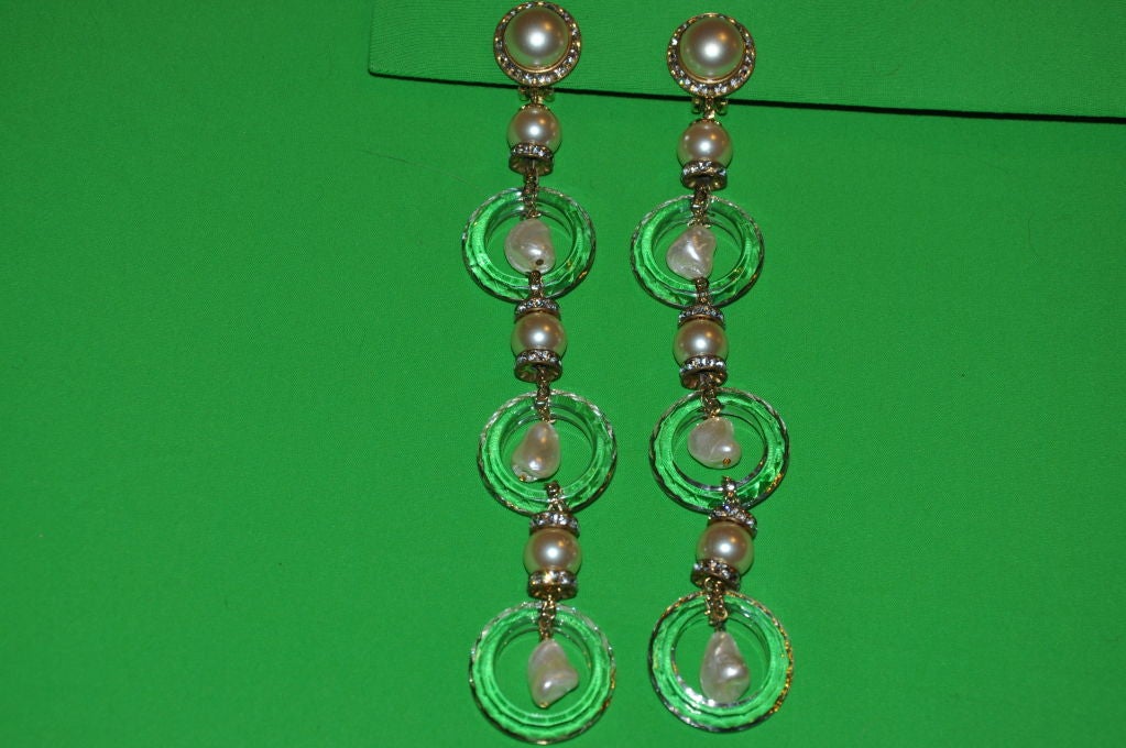 These clip on earrings have polished clear glass rings accented with pearls and rhinestones. The glass catches the light and slimmers with movement.<br />
   The total length is 6 3/4