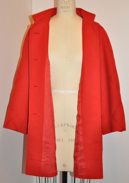 This classic Italian-red fully lined wool car coat has detailed supreme top-stitching along with hand-sewned button holes. The coat give a very slight suggestion of a flared coat with two huge patch pockets in front.
   The front has four (4)