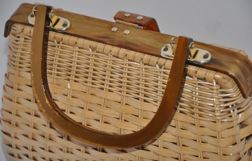 Beige with tan Lucite frame wicker handbag is wonderfully detailed with a warm multi-shade Lucite frame top unlike most run of the mill wicker bags. Gold hardware along with the lucite accents the tan-color wicker.
   Height of the bag measures 7
