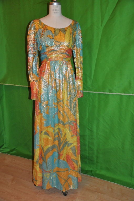 This fabulous maxi dress is multi-colored lame in colors of oranges, tangerines, greens, and turquoise with micro sequins scattered on the bodice and sleeves. The dress is fully lined in yellow silk. The tie belt is detail with multi-colored Ostrich