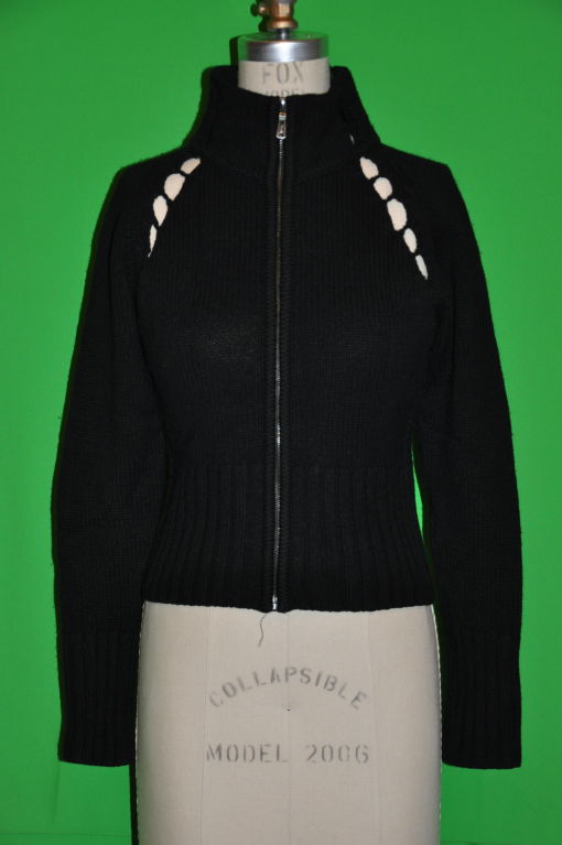 Le pull Yves Saint Laurent a un col haut avec le logo YSL sur le fermoir de la fermeture éclair. La longueur du devant et aussi du dos mesure 20