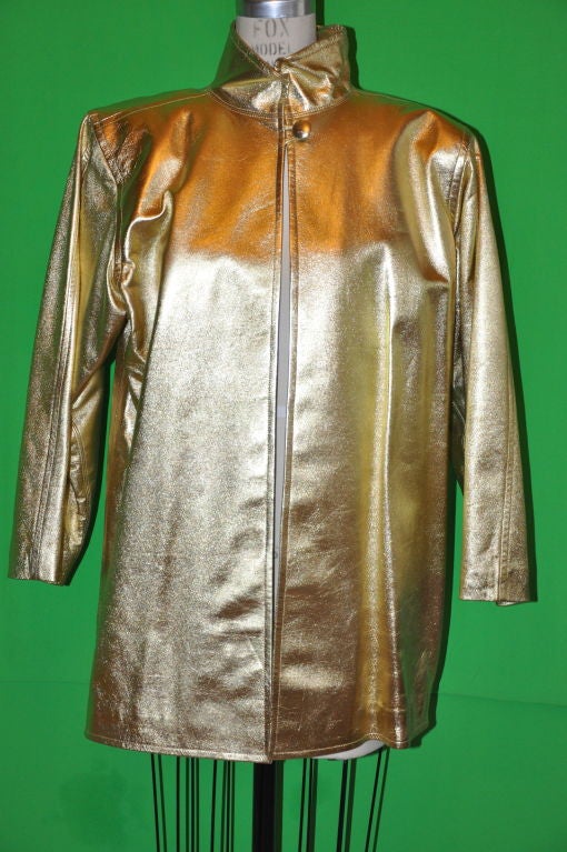 Yves Saint Laurent Rive Gauche gilded gold calf-skin coat has a stand-up collar of 3 inches;. There's a single gold leather covered button with a additional button on interior hem. The domain sleeve measures 21 1/2 inches;, circumference is 13
