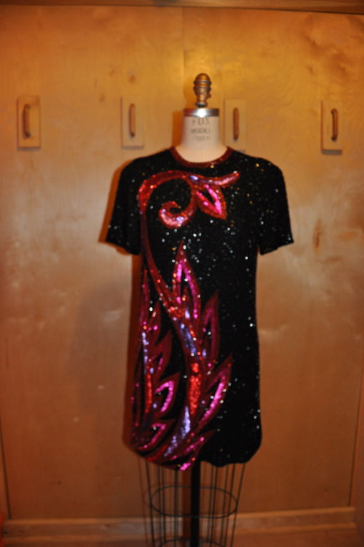 This iconic Bob Mackie mini Black cocktail dress is of silk chiffon and is fully lined in black chiffon also. The dress is embellished with Black, Ruby red and also fuchsia colored bugle beads. There are also violet and fuchsia sequins