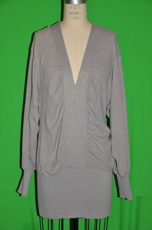 La tunica di Stella McCartney può essere indossata come top o come mini abito. Il top in maglia è grigio con micro fili dorati luccicanti. La parte anteriore misura 19 1/4