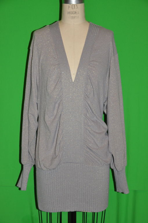 Stella McCartney tunic top can be worn as a top or as a mini dress. The knitted top is gray with micro shimmering gold threads. The front measures 19 1/4