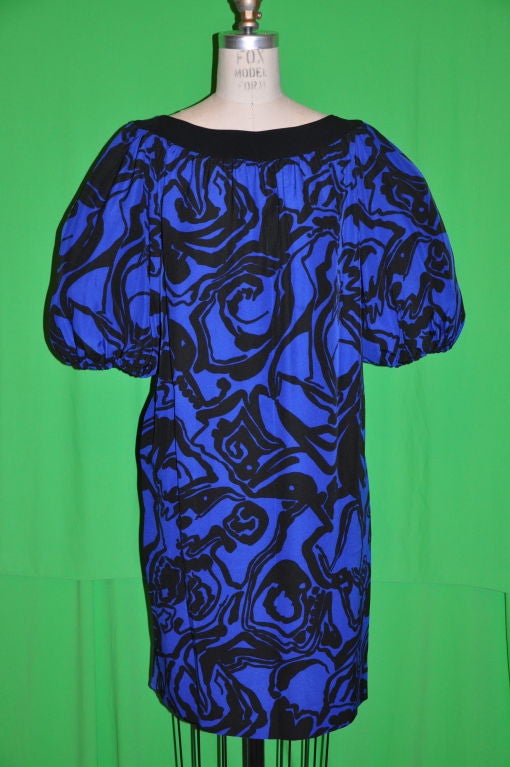 This signature bold Lapis with Black accent Yves Saint Laurent Rive Gauche peasant dress can be worn belted or as shown. The dress is made of silk crepe de chine and there are two hidden side pockets. The black neckband measures 1 3/4