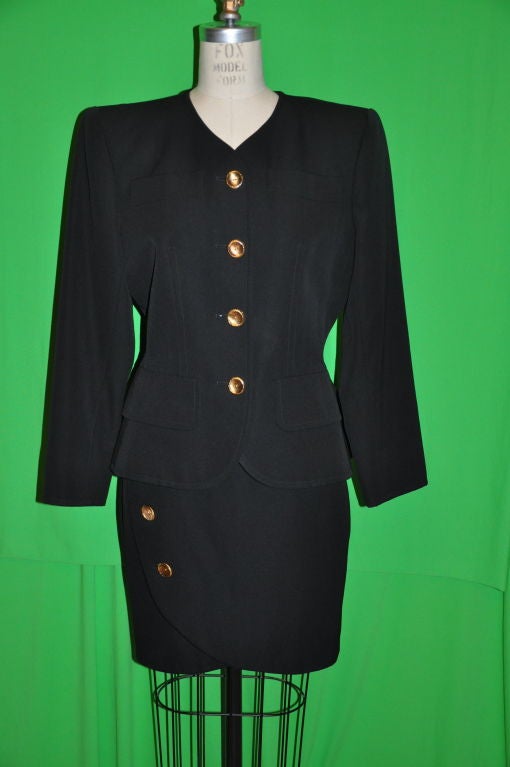 This Yves Saint Laurent black wool suit has a wonderful wrap skirt that fully lays flat and can be adjusted to make smaller or larger either way by moving the location of the buttons by the tailor if needed. The jacket has a slight peplum cut with