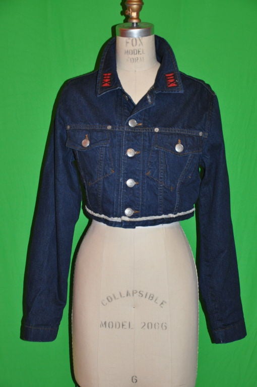       Jean Paul Gaultier's crop denim jacket with pocket flaps in front. There are five (5) metal buttons on the front, and also two (2) metals buttons on both sides of the jacket near the waistband to adjust the fit if necessary. There's also