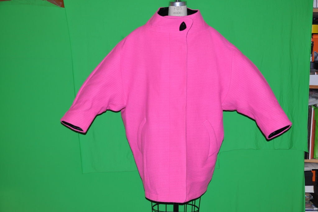 This Rare, never worn, still with tags, Iconic Thierry Mugler signature Avant-Garde Neon Fuchsia coat has black velvet interior edging along the opening front, neck, and sleeve cuffs. The front has a seven (7) snap closing. The collar is cut wide