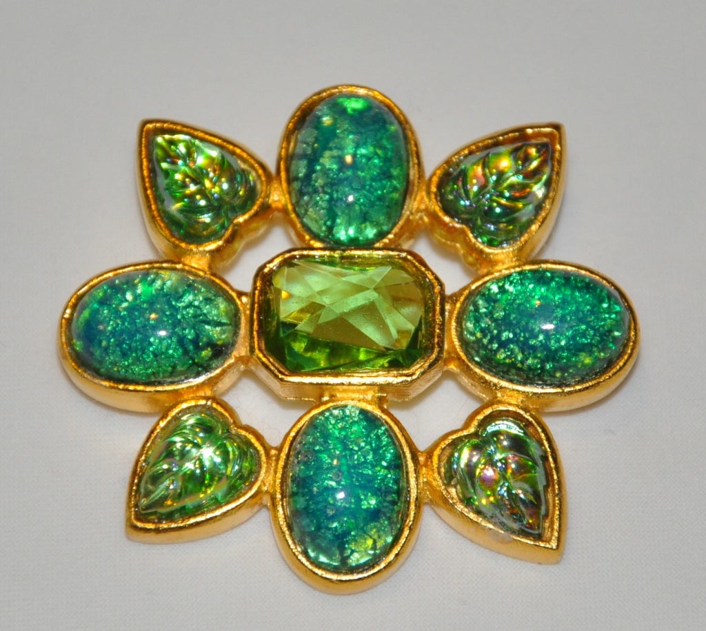 This Jean & Kuniko brooch is from poured glass set in gilded gold-tone hardware. The center stone is clear-colored pour glass. The brooch measures 1 7/8