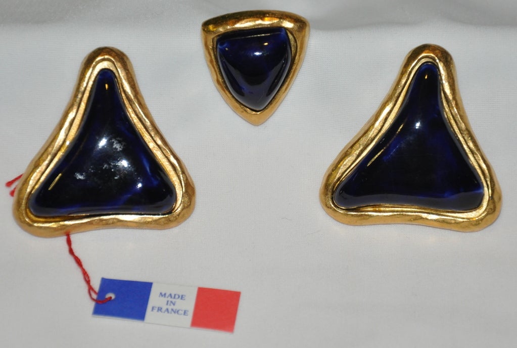       Guy Laroche gilded yellow gold clip-on earrings with matching tack pin are centered with deep-navy colored baked enamel. The clip-on earrings measures 1 1/2