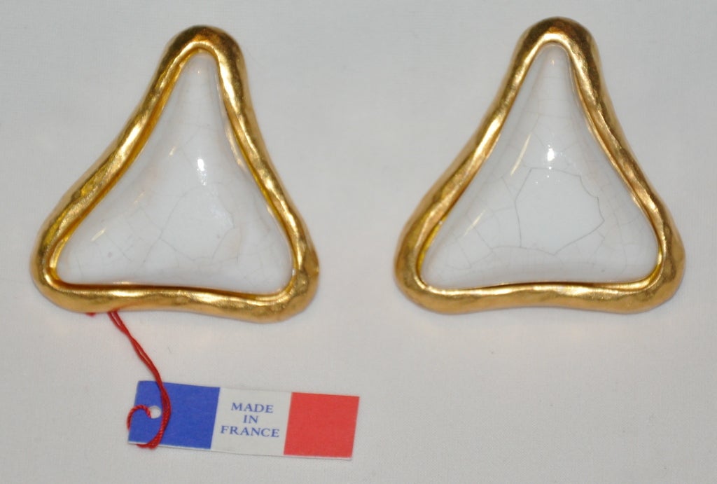 Guy Laroche clip-on earrings are in gilded gold with white baked enamel set in the center. both earrings are signed with a name plate on back. The earrings measures 1 1/2