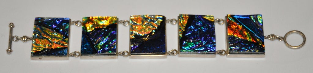 This signed Terika Blake Sterling Silver bracelet is set with poured glass of iridescence hues of all spectrums of colors in a rich deep shade. This huge, chunky bracelet measures 9