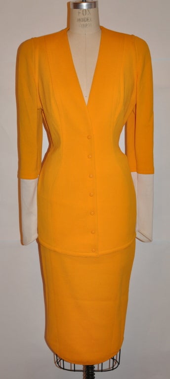 Thierry Mugler banana hue skirtsuit is in textured cotton knit. The jacket has fitted sleeves and has white ribbed cotton towards the cuffs. the front has hidden snap detail along with a asymmetric hemline. The jacket measures 20