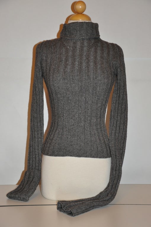 This Ann Demeulemeester charcoal wool turtleneck has over-extended sleeves which can be worn as shown, or folded over. There is eyelet detailing along the front chest area right below the front neck. The material is a wool blend of 40% wool, 50%