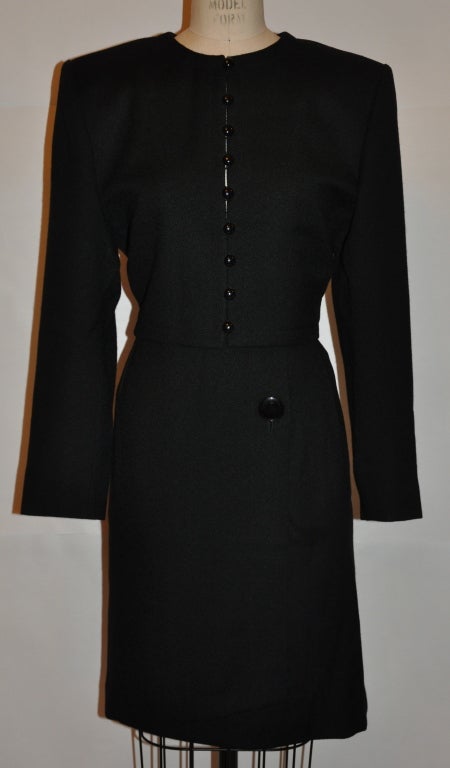 Yves Saint Laurent Costume jupe deux pièces en laine noire a une jupe enveloppante avec un seul gros bouton et un crochet caché et un œil pour la fermeture. La jupe peut être allongée de quatre pouces sans changer l'apparence du costume.<br />
  La