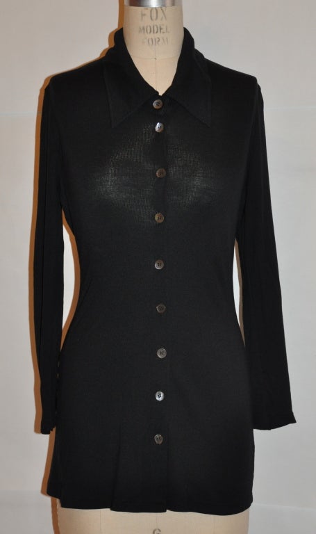 Ann Demeulemeester black body-hugging blouse has a button front and also with  a three (3) button detail on the sleeves cuff. The front is 25