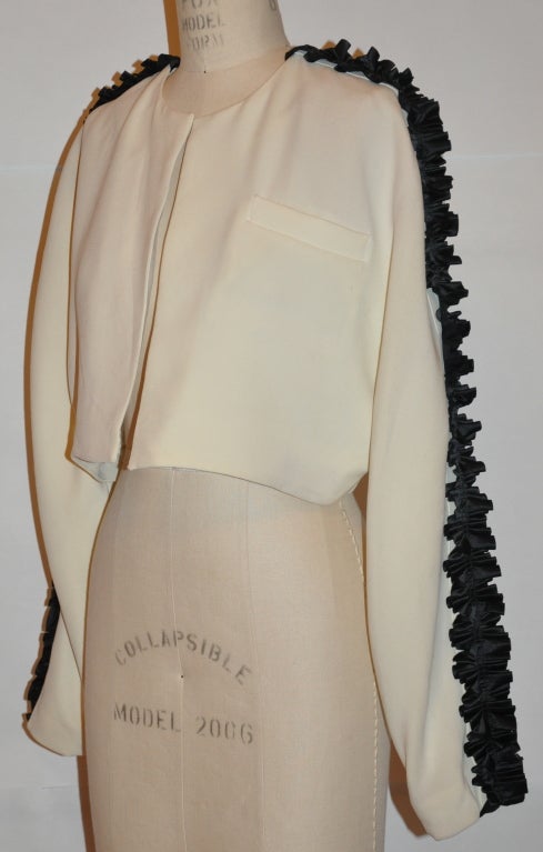 Jiki Monte Carlo of Monaco fully-lined beige wool waist jacket has black silk taffeta ribbon detailing on the sleeves. The silk taffeta ribbon measures 2 inches; in width. The jacket has a breast pocket.
   Neck-to-sleeve cuff measures 31 inches,