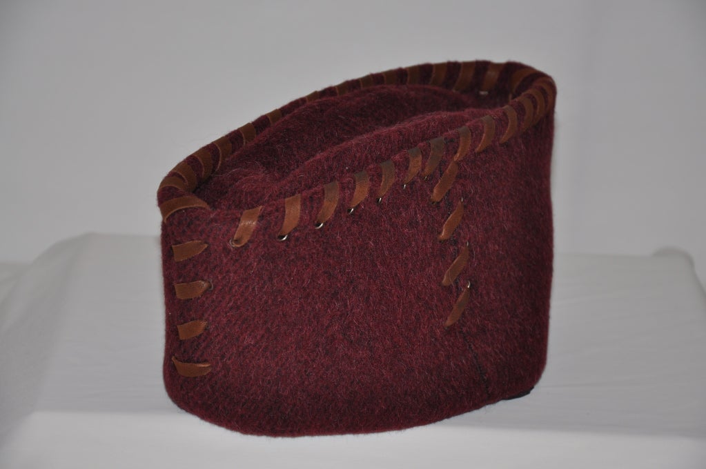 Prada's Burgundy/brick colored Alpaca wool close-fitting hat with brim turned up evenly all around, like cap worn by sailors. On all borders are detailed with leather strips lace-styled. Height is 5 1/2