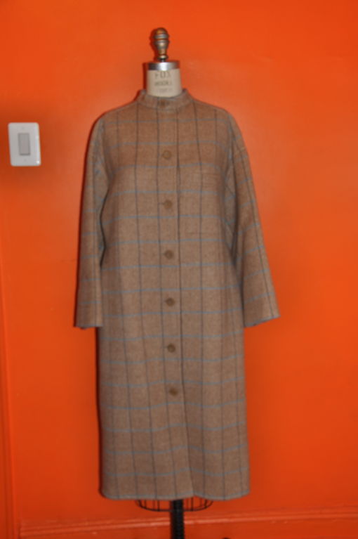 This double-faced felted Apache-wool coat is block shaped along with Kimono sleeves. This camel-colored coat has strands of powder blues, charcoal and gray running throughout giving a soften appearance. There are 7 buttons in the front and a