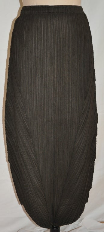 La jupe noire d'Issey Miyake, réalisée dans la matière plissée caractéristique de la marque, est de coupe asymétrique et comporte une taille élastiquée qui mesure 26
