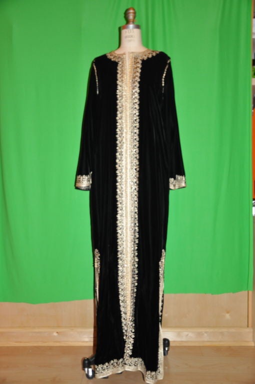 This wonderful floor-length black velvet caftan has gold thread embroidery detailing with 128-buttons in front with the option of wearing it open or buttoned up. The sleeves are bell-shaped, also with gold thread embroidery detailing. On both sides
