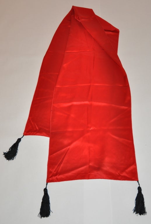 Red silk crepe de chine scarf has accents of black tassels on each corner of the scarf. The scarf measures 14
