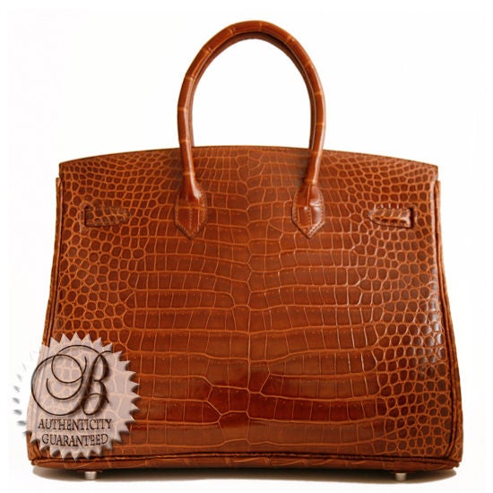 This is an authentic HERMES 35cm Miel Shiny Crocodile Birkin Bag. This is a luxurious honey brown – a classic timeless bag. The bag has a glossy exterior with classic Birkin lines, and Miel in color...one of the classiest medium brown tones around.