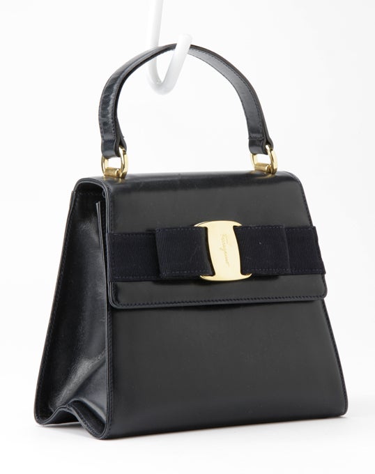 This is an authentic, and hard to find, Lady Vara Handbag by Salvatore Ferragamo.  Done in rich box calf leather in the deepest, darkest navy (almost black) with golden hardware, this bag has a signature Ferragamo grosgrain bow with golden hardware