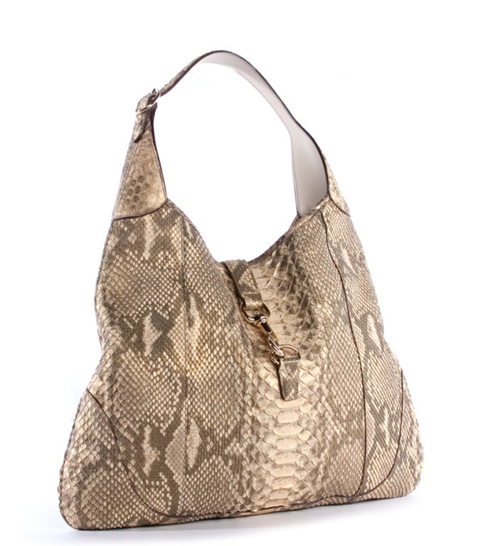 This is an authentic Gucci Beige Python Jackie O Hobo Bag. It is done in luxurious beige and caramel colored python skin with pale gold hardware and dark undertones. It features a single flat adjustable leather handle, as well as a flap tab with