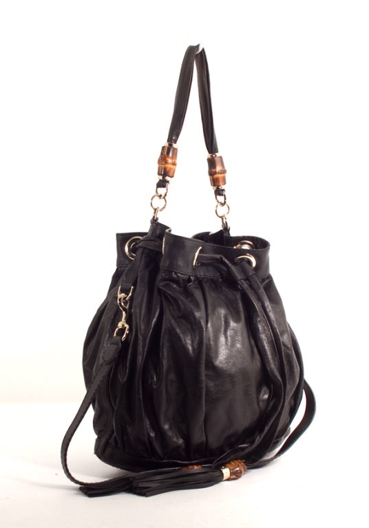 This is an authentic GUCCI Bamboo Beads Bucket Drawstring Bag. Done in lovely black leather, it features an exterior pleated design with two flat leather handles, silver hardware, and a drawsting closure. There is one shorter handle and one longer