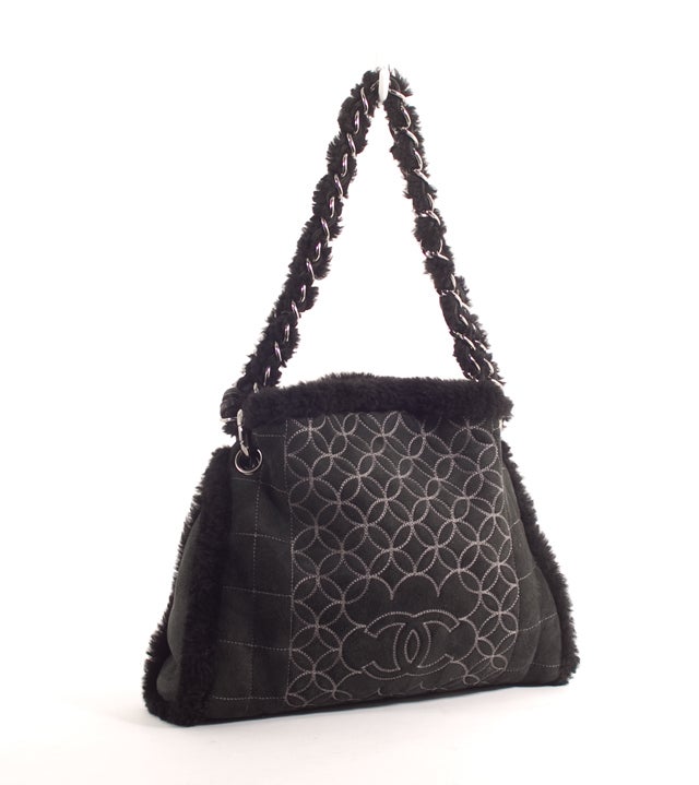 This is an authentic CHANEL Black Quilted Leather Suede Shearling Bag. It is done in luscious black suede and shearling. This bag features a double chain and suede shearling handle, a unique front design with Chanel logo, snap closure and shiny