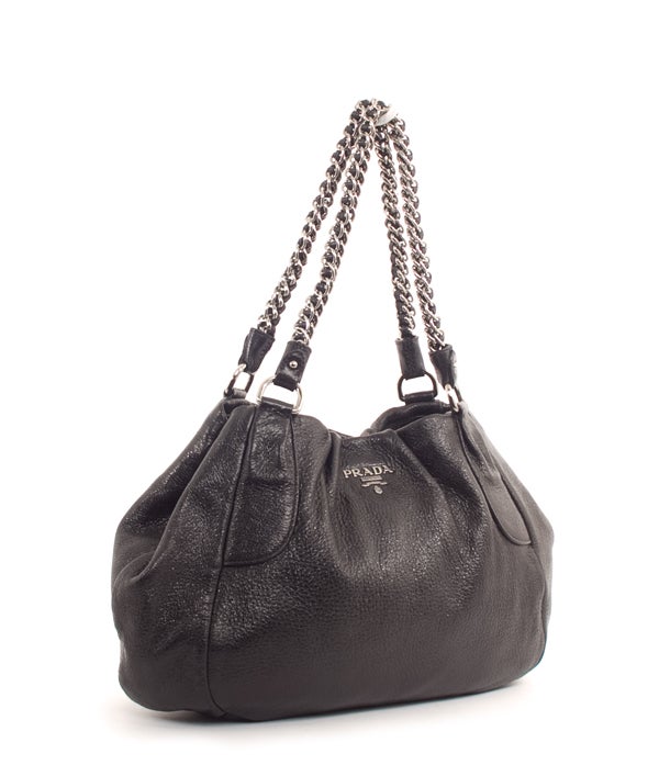 This is an authentic Prada bag. This lovely bag is done in black leather that has a glitter shine to it. This bag features silver hardware and a dual chain and leather handle. The interior is done in coordinating black textile with the Prada logo
