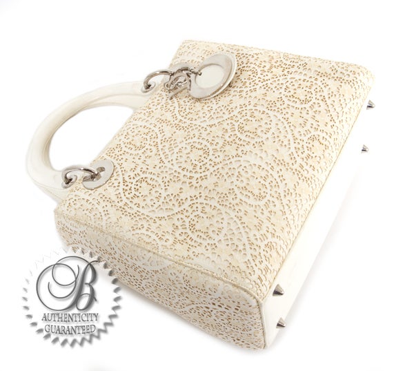 This is an authentic Christian Dior Classic Lady Dior Ivory Lace Bag. It is done in signature Christian Dior Cannage style in ivory lace with elegant silver hardware. The bag features two comfortable handles, a zip top closure, a flat bottom and