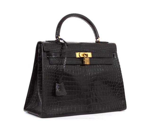 This is an authentic HERMES Black Porosus Crocodile 32 cm Kelly Bag Authentic. It is done in gorgeous Crocodile material with gold hardware. It features a single leather handle and the signature Hermes flap top closure with leather strap over round