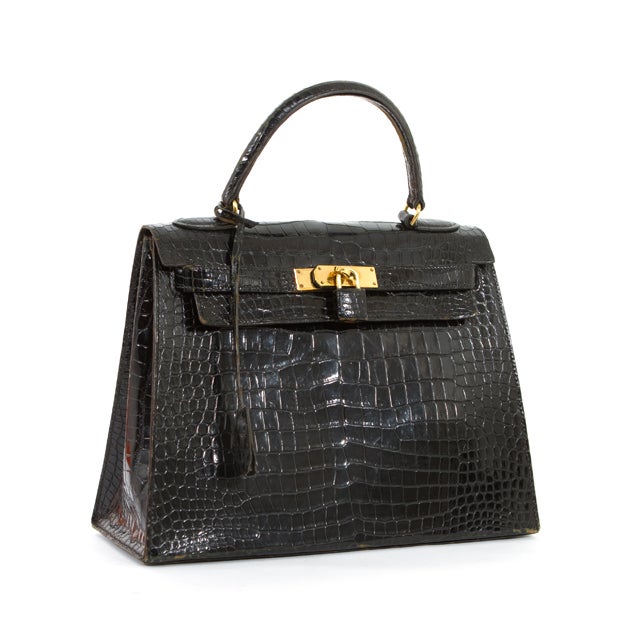 This is a guaranteed authentic Hermes Kelly Bag, done in elegant black crocodile with gorgeous gold hardware. It features a spacious interior with a top handle and leather draw strap closure with a rotating clasp. The interior is lined in
