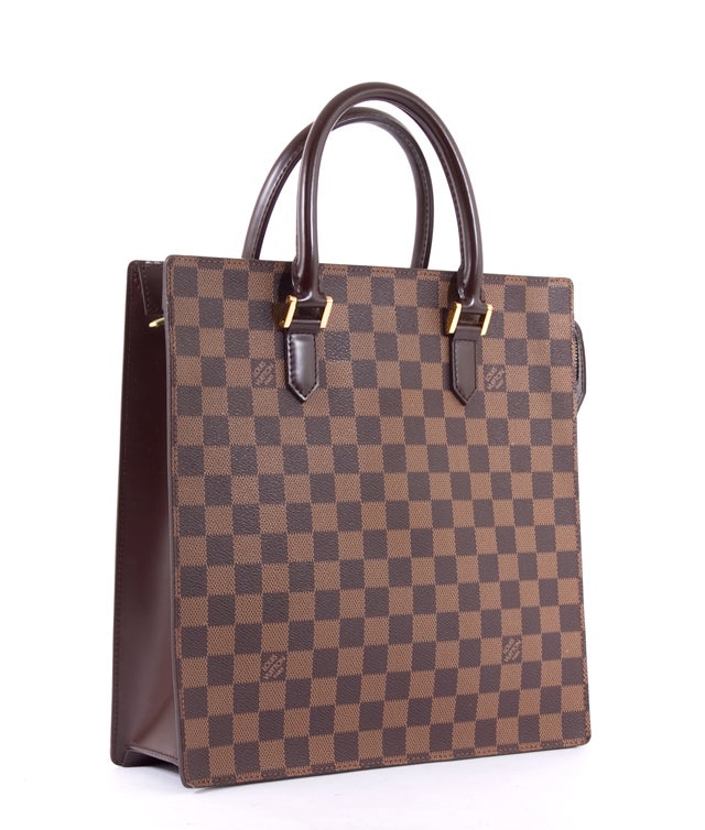 This is an authentic LOUIS VUITTON Damier Vernice Sac Plat Bag. It is done in signature Louis Vuitton damier ebene canvas with chocolate leather trim and gold hardware. It has dual rolled leather carrying handles and is large enough to fit