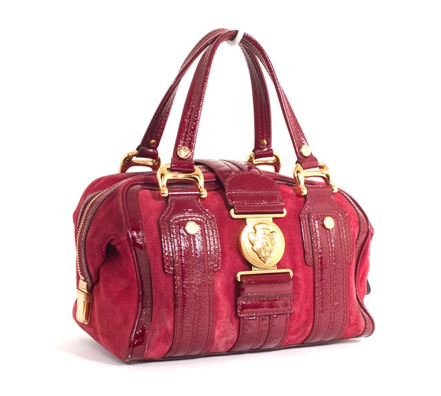 This is an authentic Gucci Aviatrix Bag. Done in Red Leather and Suede, the bag is a classic Boston shape with a flat bottom, dual handles and a buckle over closure, as well as zip top closure and gold-Toned hardware. The bag has a roomy interior