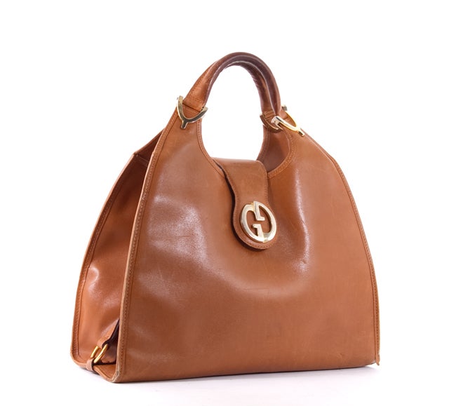 This is an authentic GUCCI Stirrup Vintage Hobo Shoulder Bag Saddle Brown. It is done in luxurious tan leather with golden hardware and the most sophisticated sheen. It features two rolled leather handles, a flap tab with Gucci logo and snap
