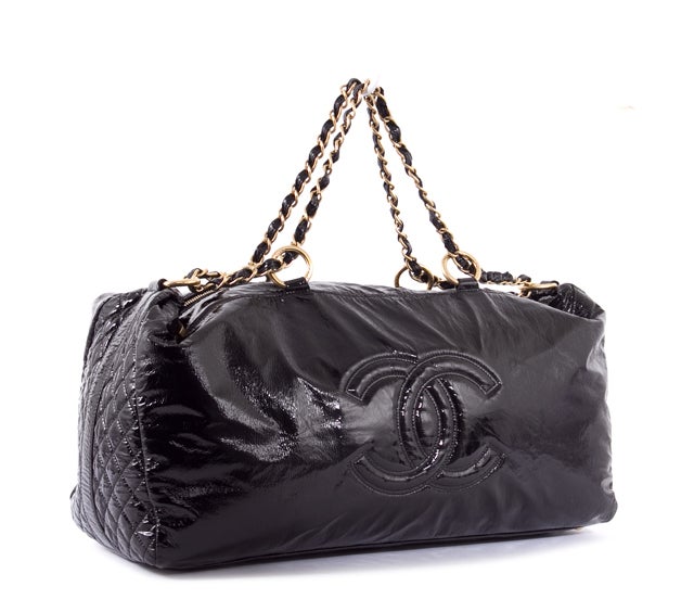 This is an authentic CHANEL Rock and Chain Oversized Boston Duffel Bag Handbag. Done in lovely black vinyl material, this Chanel bag features a large CC  logo on the front, quilted side accents, a dual vinyl chain link handle with bright gold
