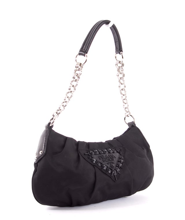 This is an authentic PRADA Black Nylon Sequined Logo Evening Pochette Bag. It is done in a black nylon material with black leather accents and silver hardware. It features a black leather and chain link handle and a beaded/sequined Prada emblem on