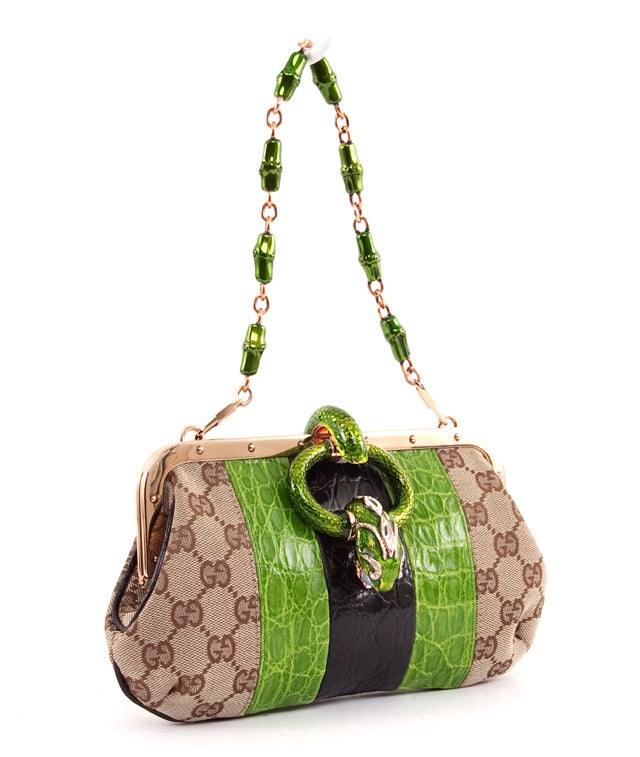 This is an authentic GUCCI Limited Edition Monogram GG Swarovski Serpent Dragon Head Clutch Bag. This bag features rose gold toned hardware with green accents most notably at the removable shoulder chain. The bag closes with a rotating ring that
