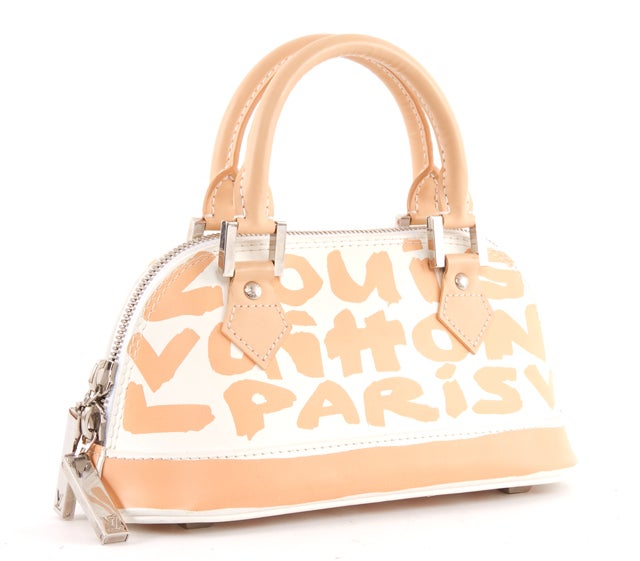 This is an authentic LOUIS VUITTON LTD ED. Stephen Sprouse Peach White Graffiti Alma Bag. This special edition alma bag features a white color base with an overlay of peach colored print graffiti and matching base trrim. This adorable bag has a top