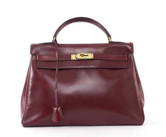 This is an authentic HERMES Burgundy Box Calf Leather 32cm Kelly Bag. It is done in classic burgundy leather with lovely golden hardware. This bag features a single rolled leather handle and the signature Hermes flap top closure. The interior is