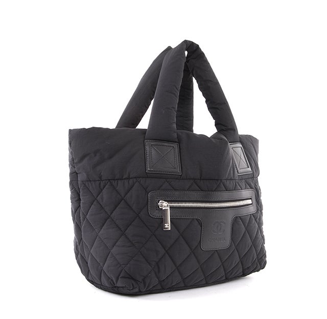 This is an authentic Chanel Coco Cocoon Bag. Done in black nylon, this bag is puffy and light weight. It has quilting on the exterior and can be reversed to be worn with the red interior facing out instead, as well. The bag has two puffy shoulder