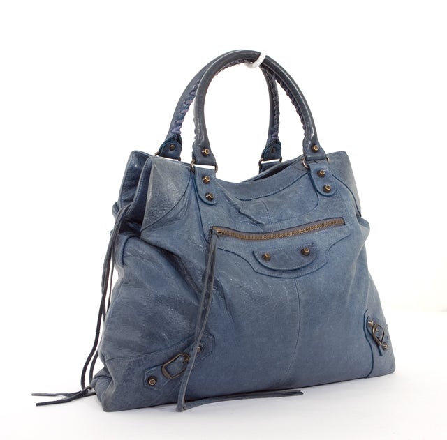 This is an authentic BALENCIAGA Cornflower Brief Bag.  From 2007 and done in soft, supple Chevre leather…the bag is signature Balenciaga …soft, buttery with brass-studded hardware. The dual rolled handles are crafted with braided leather. This bag