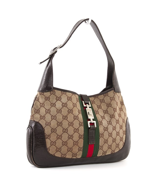 This is an authentic, Gucci Jackie-O Hobo Bag. This bag is the perfect size and shape for everyday wear! It is done in Gucci GG monogram canvas that is trimmed in smooth leather and has the signature Gucci Stripe down the center, with silver-toned