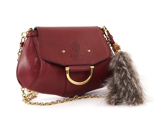This is an authentic Gucci Bag. It is done in stunning burgundy leather and features gold-toned hardware, a flap closure, a detacheable shoulder strap, and fur and bamboo accents. The interior is done in white canvas and includes a side flat pocket