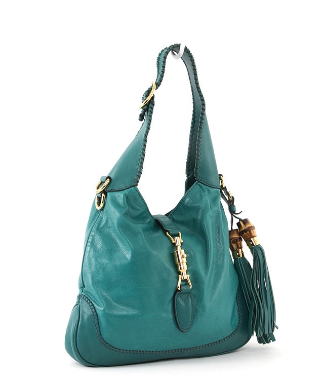 This is a guaranteed authentic GUCCI 'New Jackie' Hobo Bag. Done in amazing teal blue leather, this bag features double bamboo side tassels, leather trim details and polished golden hardware. There is also a beautifully detailed whipstitched buckle