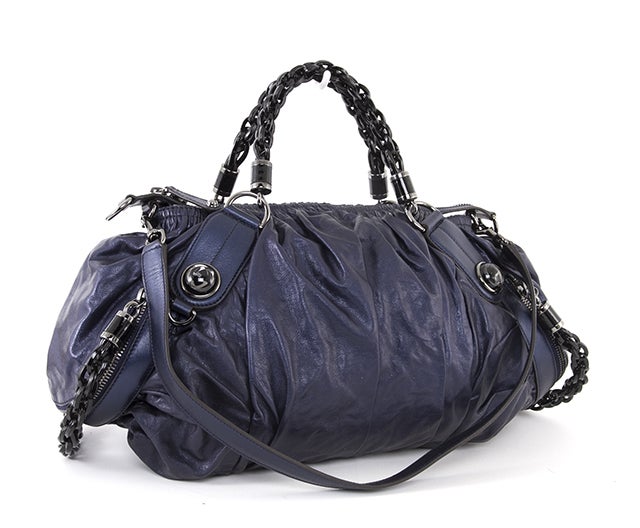 This is an authentic Gucci Bag. This unique piece resembles a small duffle bag and provides the same amount of great space! It is done in soft navy blue leather with silver-toned hardware and plastic chain link handles and side zipper pulls. It